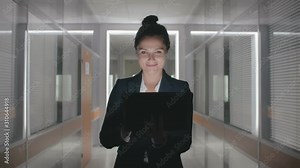 Young happy attractive caucasian businesswoman formal suit walking through office hall corridor in slow motion holding laptop computer looking for documents contract details. Lady smiling Stock Video
