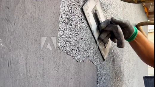 Plastering the external wall with marble chips. Using a spatula, apply decorative marble plaster to the wall. The process of applying a layer of gray plaster. Modern materials for home decoration