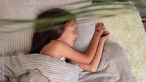 Adorable toddler resting peacefully. Childhood innocence in the bedroom. Morning relaxation in bed. Comfortable naptime for kids. Little brown haired girl sleeping on bed with soft pillow at home
