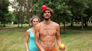 Girl grabs balls as guy is juggling