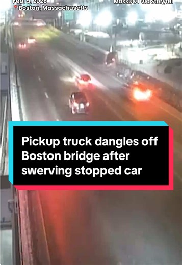 A newly released video shows a pickup truck dangling off the side of the Leonard P. Zakim Bunker Hill Memorial Bridge in Boston, Massachusetts after swerving to miss a stopped car on February 5. The truck crashed into a barrier on the right side of the highway and dangled approximately 100 feet over the roadway underneath. No injuries were reported.