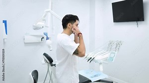 Male dentist putting on a surgical mask in a modern dental clinic. Dentist putting on a mask preparing all the instruments for an operation in a modern dental clinic. Health concept