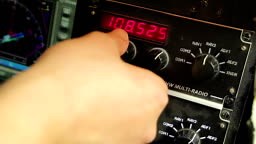 Pilot's hand turning controls on cockpit panel, connecting to radio...
