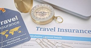 Travel insurance and service concept : Top view of travel insurance application form, an insurance tag, a compass, a laptop. Travel insurance covers costs and losses associated with traveling.