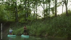 Couple of surfers paddling on surfing boards, people rowing standing on surfboards. Sports young family using paddleboards. Summer sport, outdoor vacation, extreme holidays. Sports professional school