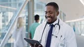 Black man, doctor walking through hospital and tablet, online medical...