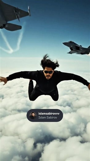 Islam Sobirov on Instagram: "1 . . Ultra-realistic cinematic scene of me floating and falling mid-air above the clouds, captured in a dynamic upside-down pose with legs bent and arms slightly raised. I am wearing a black hoodie, black pants, a black cap, sunglasses, and red sports shoes. Two futuristic stealth fighter jets fly extremely close above and below the character, with realistic motion blur, heat trails, and speed distortion. High-altitude sky environment with soft cinematic lighting, r