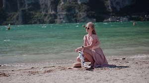 Woman on the beach enjoying sunset near lake.