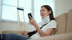 Woman stressed over medical expenses smartphone accident fracture broken bone injury with leg splints in cast, neck splints collar, sling support arm. Social security and health insurance concept.