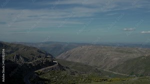 Serra da Estrela mountain range view, showcasing rugged terrain, winding roads, and expansive valleys under a blue sky