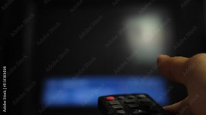 close-up of a man's hand holding a TV remote control. a man's finger pressing the buttons on an analog TV remote control using set top box