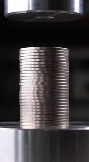 Nic Davis on Instagram: "Watch a towering stack of quarters with shimmering iridium-coated edges get slowly compressed by a hydraulic press. As the coins flatten and deform, colorless lubricant with spectral hints seeps from between them, creating a mesmerizing ASMR moment of controlled destruction."