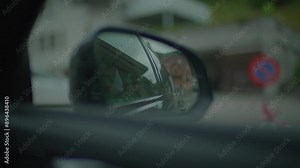 A side view mirror shows a busy urban street scene with buildings and traffic passing by