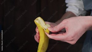 Woman peels banana, housewife is cooking fruit salad, healthy food for kids at home, fruits and vegetables in the kitchen