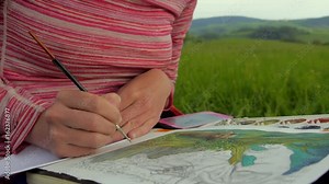 female artist paiting a jungle themed picture with watercolours, outdoors in a nature