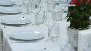 Luxury table decoration setup at a fancy restaurant. 4k video with panoramic camera movement on a table with crystal glasses and white plates.