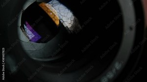 A movement of the aperture flaps on the camera lens. Aperture photo lens close-up. Multi-colored reflections of the window in the camera lens.