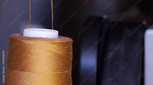 Close up of a spool of thread on sewing machine, yarn unwinds.