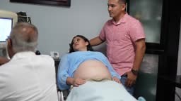 Obstetrician using ultrasound scanner on pregnant mid adult woman in...