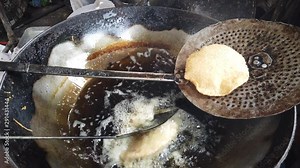 Closeup of preparing Puri, a deep-fried bread, from Indian subcontinent, eaten for breakfast or snack meal. Served with a savory curry, bhaji or sweet dish. Popular street food shot in 4K 60fps