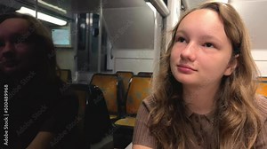 girl Riding the train there is no one She is alone she is in a brown suit beautiful with blond hair on the street, spring, trees flash by, slow motion video, she thinks. High quality 4k footage