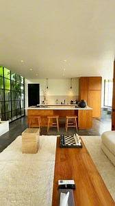 Drawing inspiration from contemporary tropical architecture, this villa seamlessly blends modern sophistication with Bali’s natural beauty. Expansive floor-to-ceiling glass panels invite abundant natural light, creating a harmonious connection between indoor and outdoor spaces. The sleek black steel frames contrast beautifully with warm wooden accents, adding depth and character to the design. A sunken lounge overlooking the infinity pool enhances the villa’s openness, while lush landscaping pro