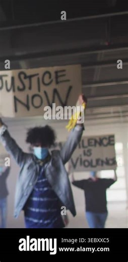 Vertical video: Activist holding justice sign and yellow bandana demanding, icons starting floating. Protest, activism, demonstration, crowd, signs, bandana, vertical video Stock Video Footage - Alamy