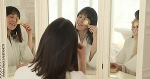 Woman carefully applies powder to her face, creating a smooth and radiant complexion. As she blends the powder, she gazes intently at her reflection in the mirror, her eyes filled with self-assurance.