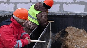 Download Construction of a house. Builders measure the facade of a brick house for free