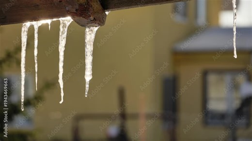 Ice icicles hanging from a roof beam during snowy thaw in winter