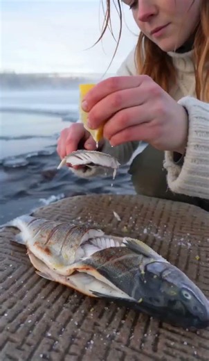 She cooked a whole fish on a hot rock by a frozen river ❄️🐟