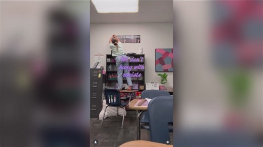 Sarah Inama hangs up 'Everyone is Welcome Here' poster