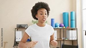 African american woman exercising indoors at a well-equipped gym, demonstrating a dynamic boxing workout pose.