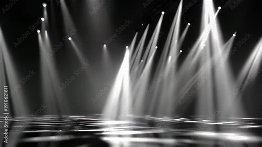 White light beams shine down on an empty dark stage, piercing the shadows in a venue ready for an upcoming performance