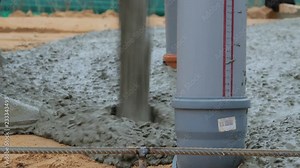 Working in black rubber boots fills cement mixture of concrete pump for screed floor heating on the ground