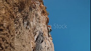 young powerful athletic man rock climber with long hair climbing on cliff. male climbing very hard route making long hard movement. extreme sport, rock climbing outdoors, training moments