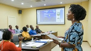An African-American female professor gives a lecture in a university auditorium to a diverse group of students