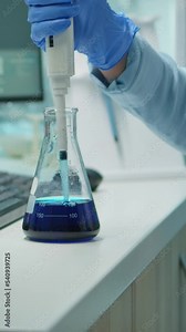 Vertical video: Close up of scientis testing liquid sample late at night using micropipette for medical treatment in laboratory. Team examining virus evolution using high tech for vaccine development