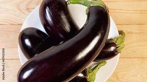 Freshly harvested purple eggplants on dish on the rustic table