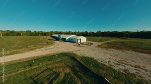 Flying over large chicken barn with FPV drone at sunset on midwestern egg farm, henhouse and feeders aerial 4k