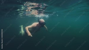 First time snorkeling. Elderly man carefully swims in the lake with mask for the first time in his life and explores underwater world. Active senior man snorkeling in the freshwater lake