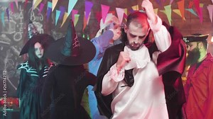 Young man disguised as a vampire is dancing funny at a halloween party. Evil vampire with big teeth dances in a pub with his crazy friends.