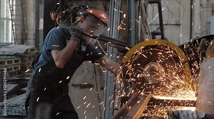 Locksmith, a factory worker cuts a metal pipe. Spark sparks at a construction site, factory premises.