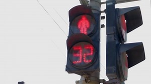 Round neon red pedestrian traffic regulator with countdown numbers. Glowing icon of a person at a pedestrian traffic light, serviceable traffic light close-up. Rules of the road, traffic control.