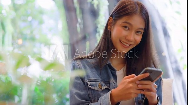 Young asian beautiful woman using smart phone in coffee shop cafe and looking at camera, typing write message on mobile, online shopping, transfer payment, internet banking