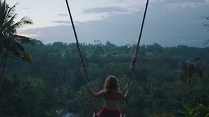Happy woman swinging over tropical jungle at sunrise travel girl enjoying exotic vacation sitting on swing in having fun holiday lifestyle freedom 4k | Premium Stock Video Footage