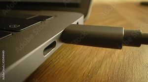 Close-up Macro Shot: Laptop on the Desk, Person Inserts USB-C Cable Adapter into Computer Port.