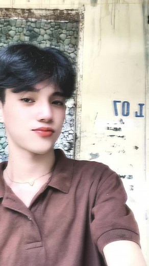 Person in Brown Shirt Against Weathered Wall