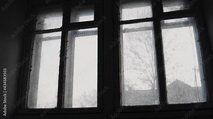 Outside the window in the old house you can see the street with trees. The camera smoothly zooms in on the dirty window