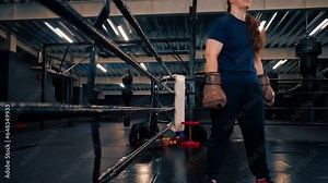 boxer girl in gloves climbs the ropes enters the boxing ring in the gym trains hard before the fight